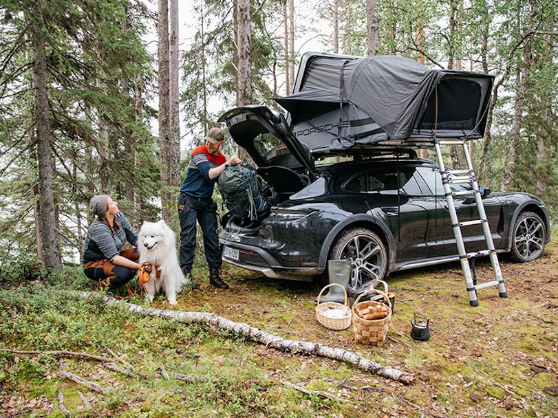 Man and woman loading Porsche with roof tent