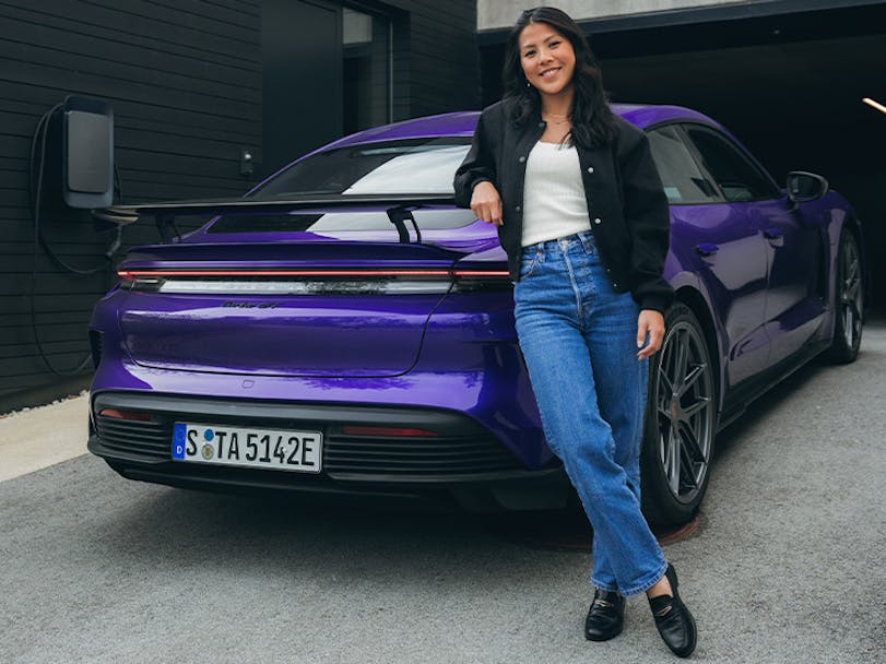 Smiling woman posing with purple Taycan Turbo GT in driveway