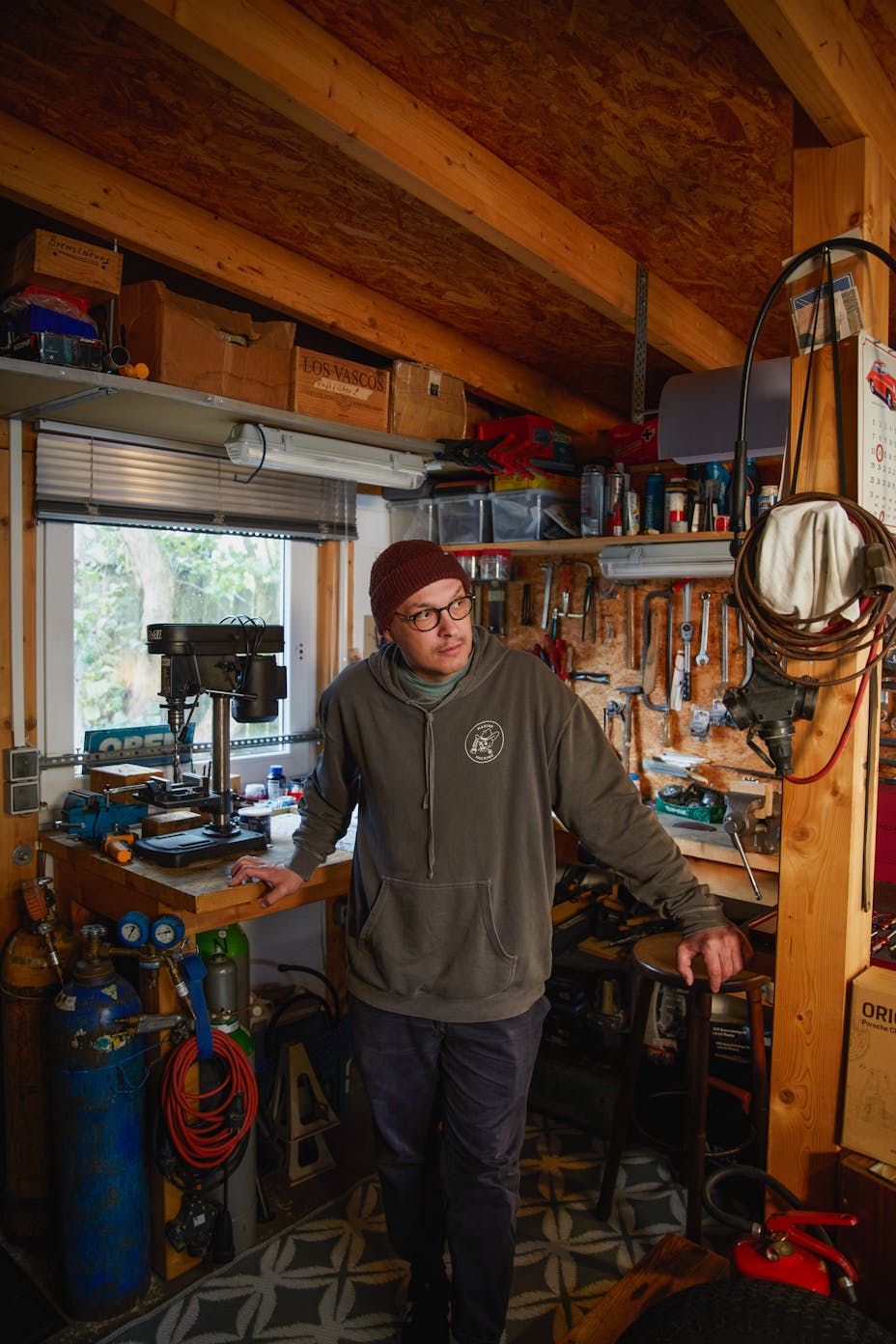 Man stands in front of busy workbench and tools wall