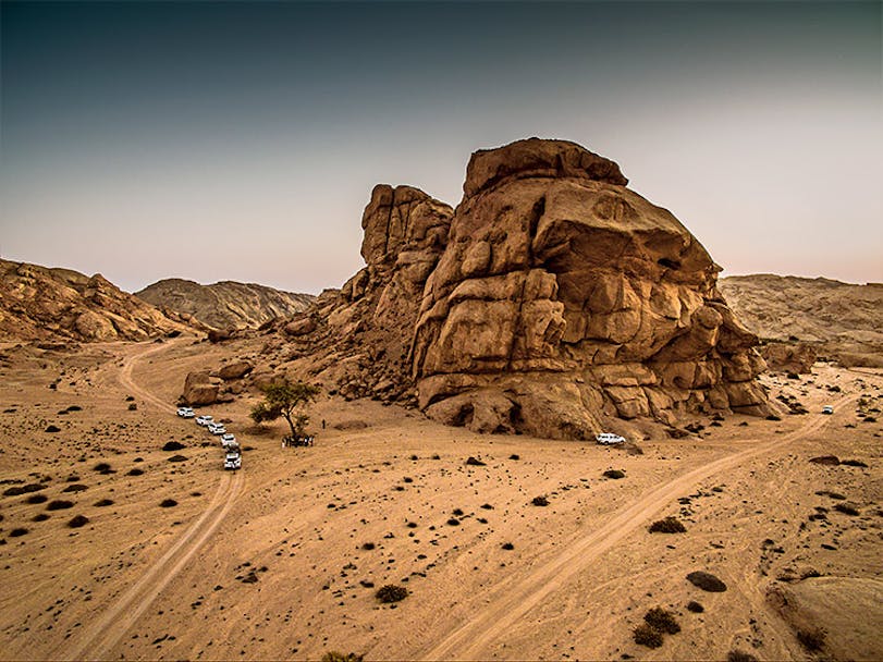 Driving through Namibian desert, large rock formation in middle ground