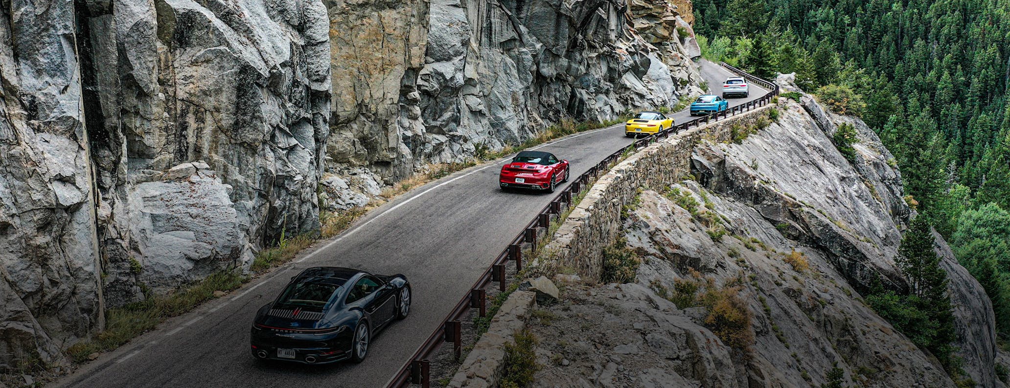 Porsche cars driving along a canyon road